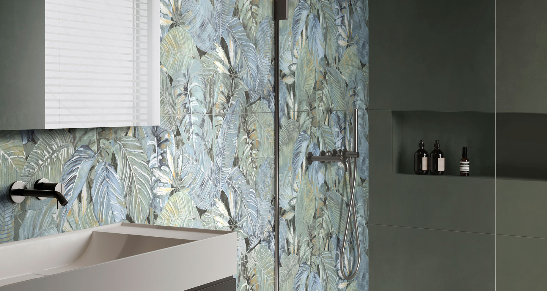 Bagno moderno con pareti decorate da foglie verdi e blu, lavabo minimalista e prodotti sulla mensola.